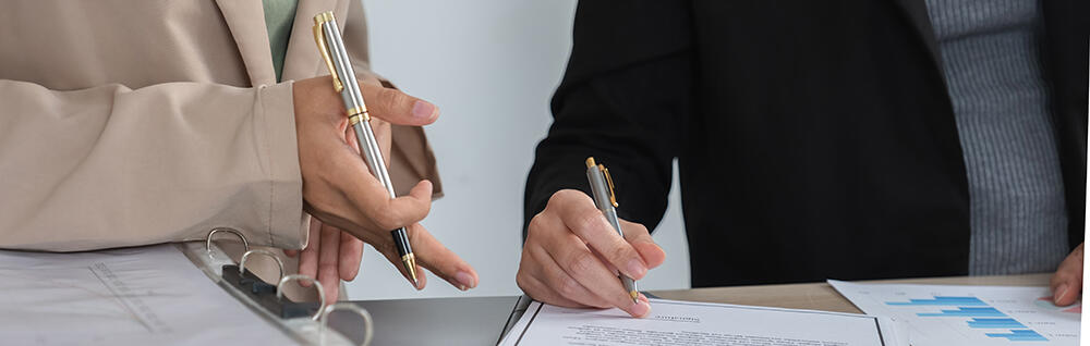 Detail of people's hands signing a document