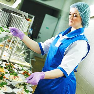 Buffet female worker servicing food in cafeteria