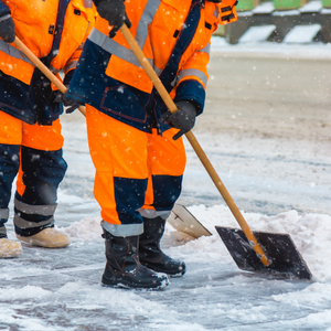 Communal services workers sweep snow from road in winter.